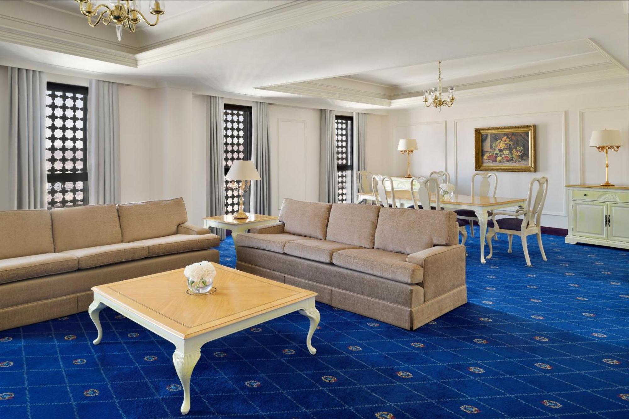 ダー アル ヒジラ インターコンチネンタル マディーナ エクステリア 写真 The photo shows a spacious and elegantly furnished living room. There are two beige sofas placed opposite each other, creating a comfortable seating area. In the center, there's a light-colored coffee table with a decorative vase on top. The flooring
